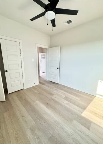 an empty room with a ceiling fan and wooden floor