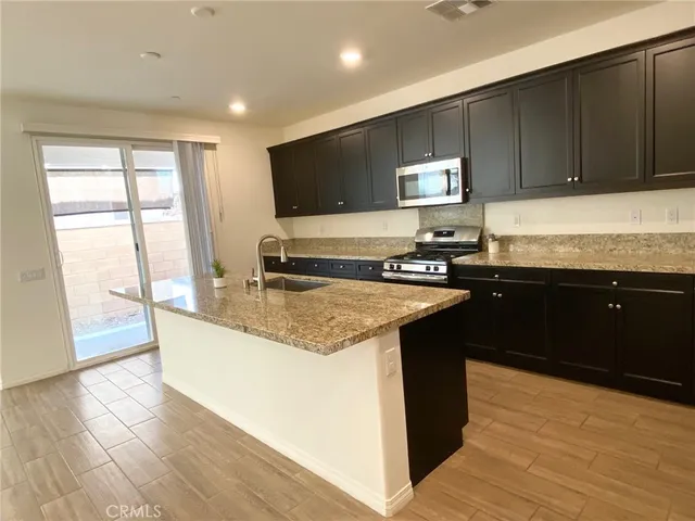 a kitchen with granite countertop a sink and a stove top oven with wooden floor