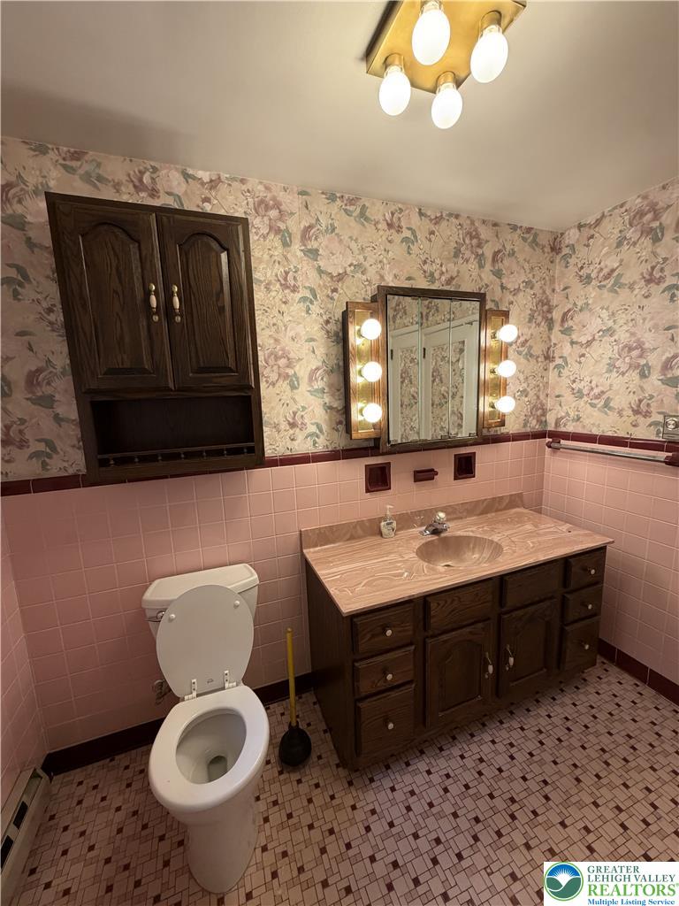 5391 Chapmans Road, Unit 2 Orefield, PA 18069 - Photo 9 of 22 A classic tiled bathroom features a functional vanity and unique floral wallpaper.