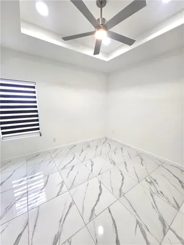 en empty room with white walls and ceiling fan