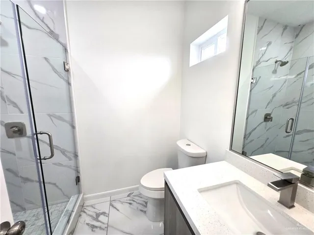 a bathroom with a granite countertop sink mirror vanity and toilet