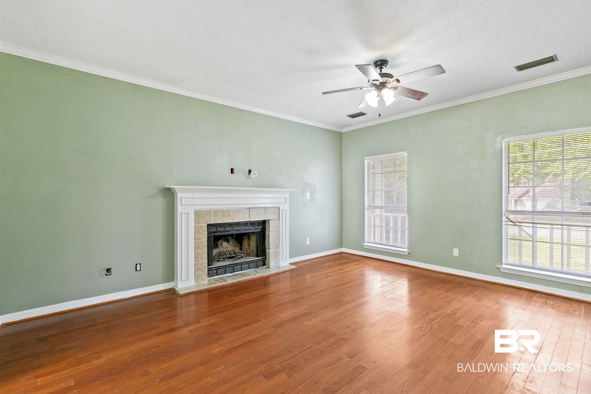 474 Ridgewood Drive Daphne, AL 36526 - Photo 15 of 57 Unfurnished living room with a textured ceiling, a tile fireplace, ceiling fan, hardwood / wood-style flooring, and ornamental molding
