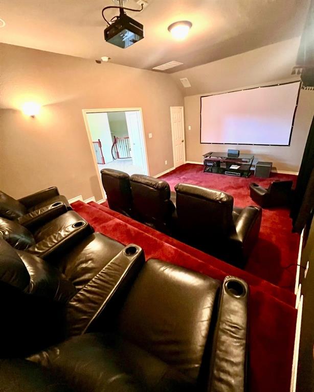 10414 Broadmoor Lane Rowlett, TX 75089 - Photo 22 of 38 Dedicated media room featuring tiered seating, a large projection screen, a ceiling-mounted projector, and red carpeting