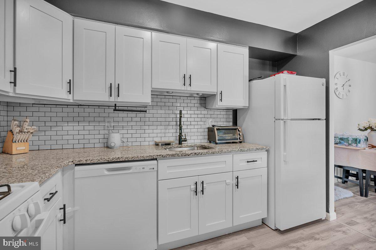 46202 Delaire Landing Road, Unit 202 Philadelphia, PA 19114 - Photo 12 of 34 a kitchen with granite countertop white cabinets and white appliances