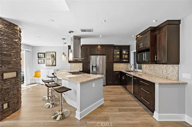 a kitchen with stainless steel appliances kitchen island granite countertop a stove refrigerator and cabinets