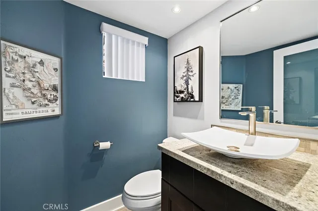 a bathroom with a granite countertop sink a toilet and mirror