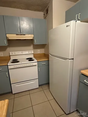 a white refrigerator freezer and a stove sitting inside of a kitchen