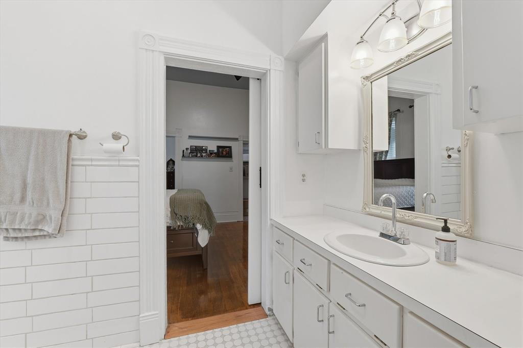 415 South Rice Street Hamilton, TX 76531 - Photo 8 of 28 Jack-and-Jill bathroom featuring a vanity with a white countertop and integrated sink, a large framed mirror, and white cabinetry