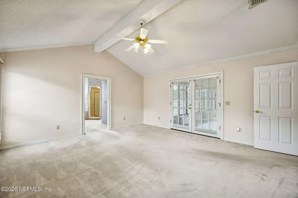 an empty room with chandelier fan and windows