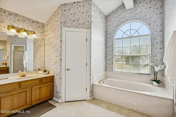 a bathroom with a tub a sink and a window