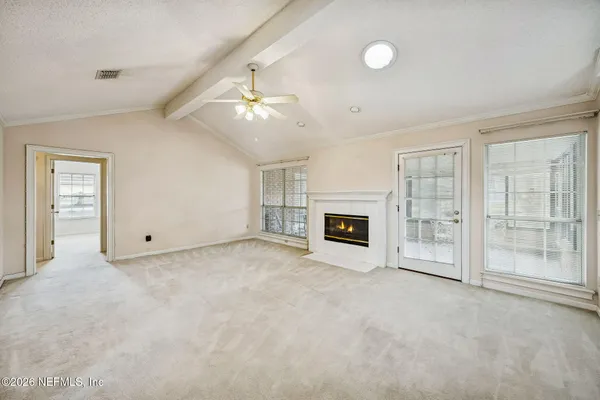 an empty room with windows and fireplace