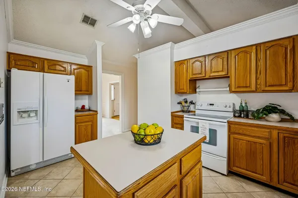 a kitchen with stainless steel appliances a sink a stove a refrigerator cabinets and dining table
