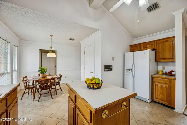 a kitchen with stainless steel appliances a stove a refrigerator white cabinets a dining table and chairs