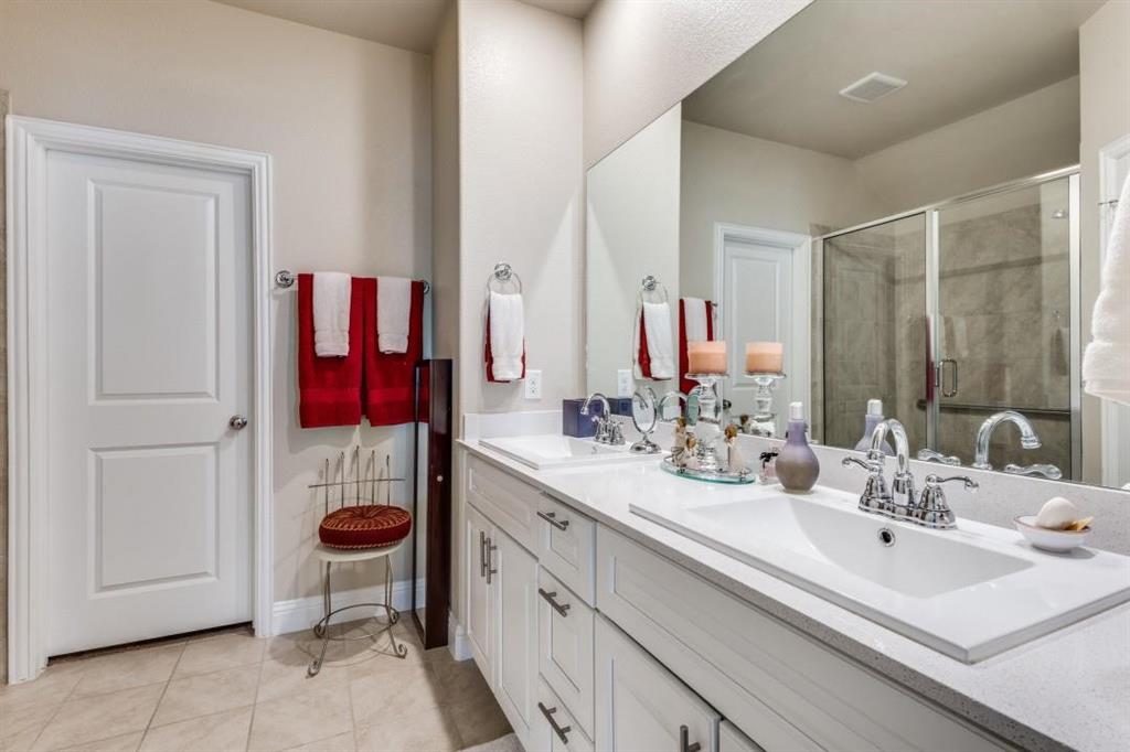 2821 Inn Kitchen Way McKinney, TX 75071 - Photo 13 of 24 Dual vanity with integrated sinks, white cabinetry, chrome fixtures, and a glass-enclosed shower
