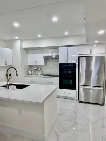 a kitchen with stainless steel appliances granite countertop a sink and a refrigerator