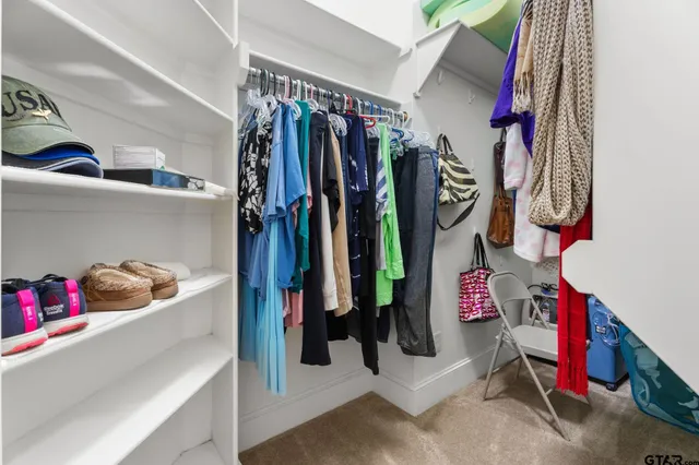 a view of walk in closet with clothes and shoes