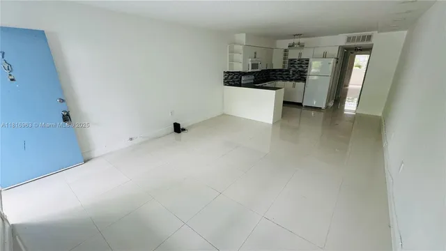 a view of a kitchen with refrigerator and white cabinets