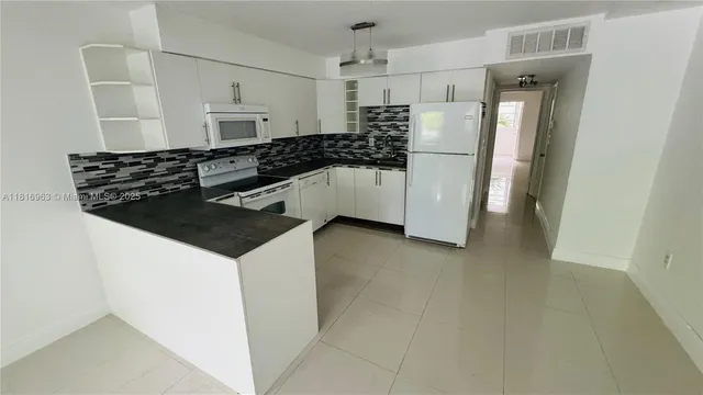 a kitchen with a refrigerator a sink and white cabinets