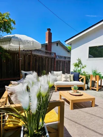 a view of a patio with couches table and chairs under an umbrella with potted plants