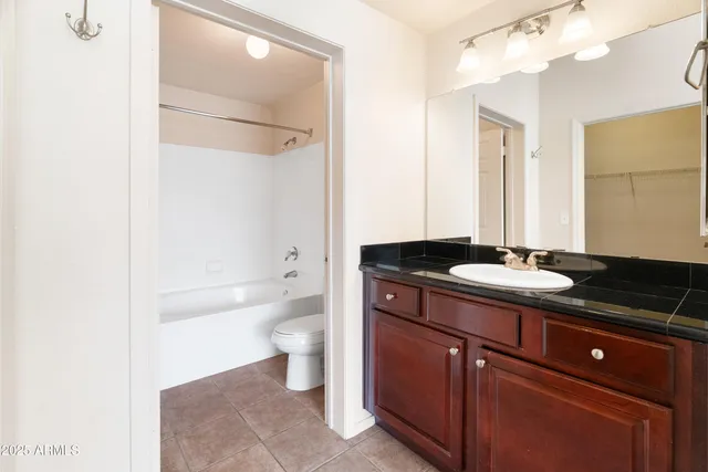 a bathroom with a granite countertop sink a toilet a mirror and shower