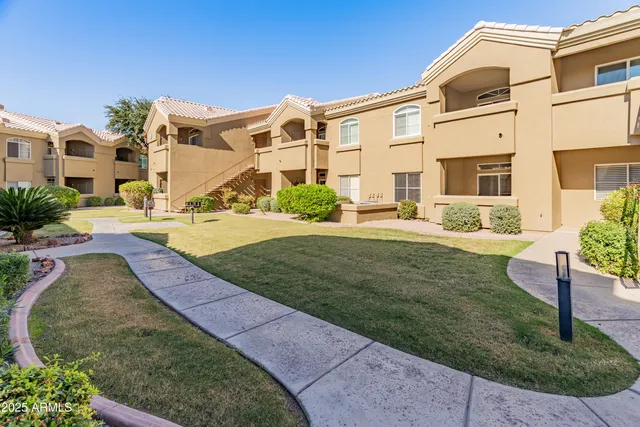 a view of a big house with a yard and plants