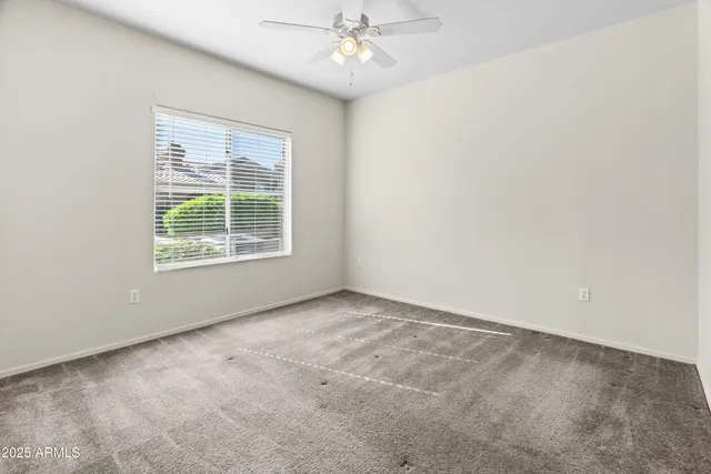 an empty room with a window and a fan