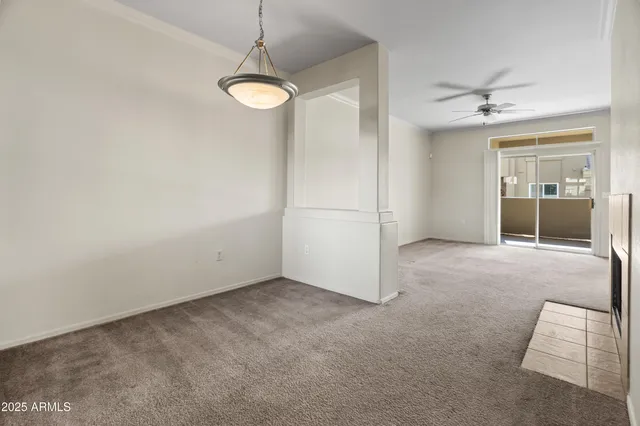 an empty room with chandelier fan and windows
