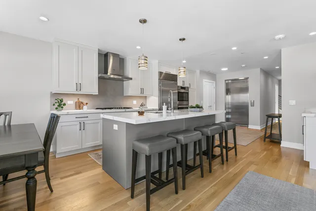 a kitchen with stainless steel appliances granite countertop a table chairs sink refrigerator and cabinets