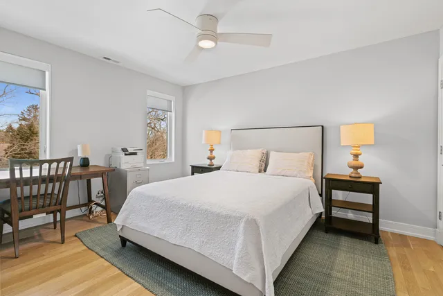 a bedroom with a bed a chair and potted plant on the dresser