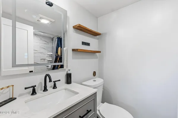 a bathroom with a sink vanity mirror and toilet