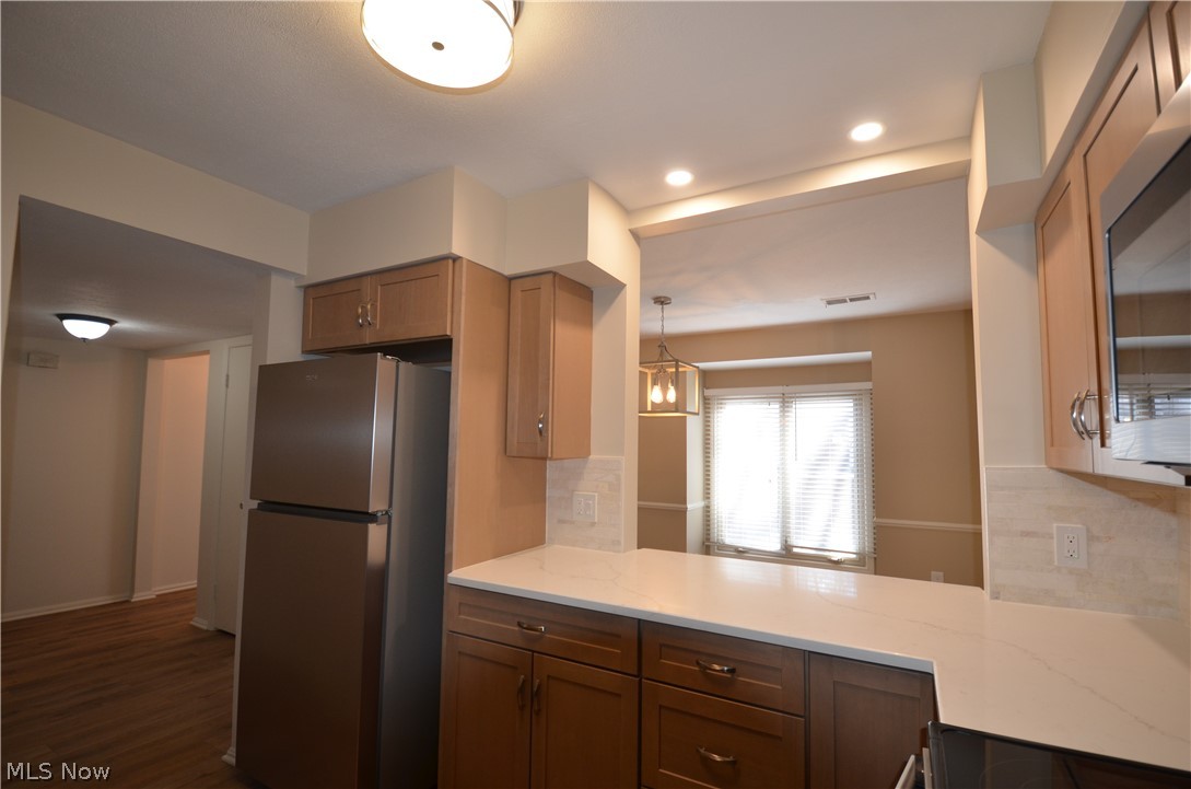 6933 West Fitzwater Road Brecksville, OH 44141 - Photo 8 of 18 Kitchen with stainless steel appliances, tasteful backsplash, vinyl floors, and light stone counters