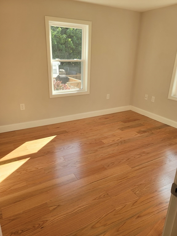 98 Uncatena Avenue, Unit L Worcester, MA 01606 - Photo 5 of 11 an empty room with wooden floor and windows