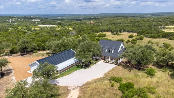 an aerial view of residential houses with outdoor space and trees all around