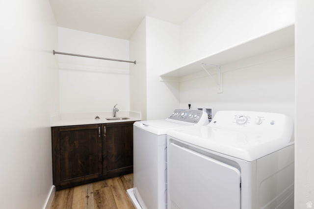3157 Deseret Drive St. George, UT 84790 - Photo 15 of 24 Dedicated laundry area featuring wood-finish flooring, a utility sink with a chrome faucet, dark wood cabinetry with chrome hardware, and a hanging rod