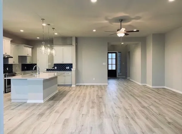 a large white kitchen with stainless steel appliances granite countertop a stove and a sink