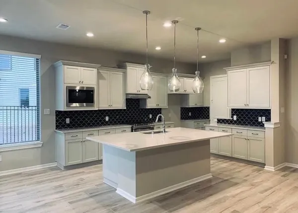 a room with kitchen island granite countertop a sink cabinets and wooden floor