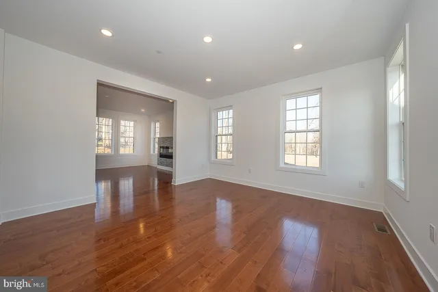 an empty room with wooden floor and windows with curtains