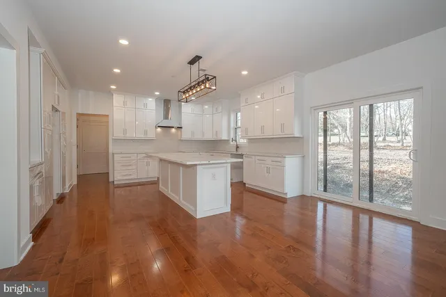 a kitchen with stainless steel appliances granite countertop a refrigerator a sink dishwasher a stove and white countertops with wooden floor