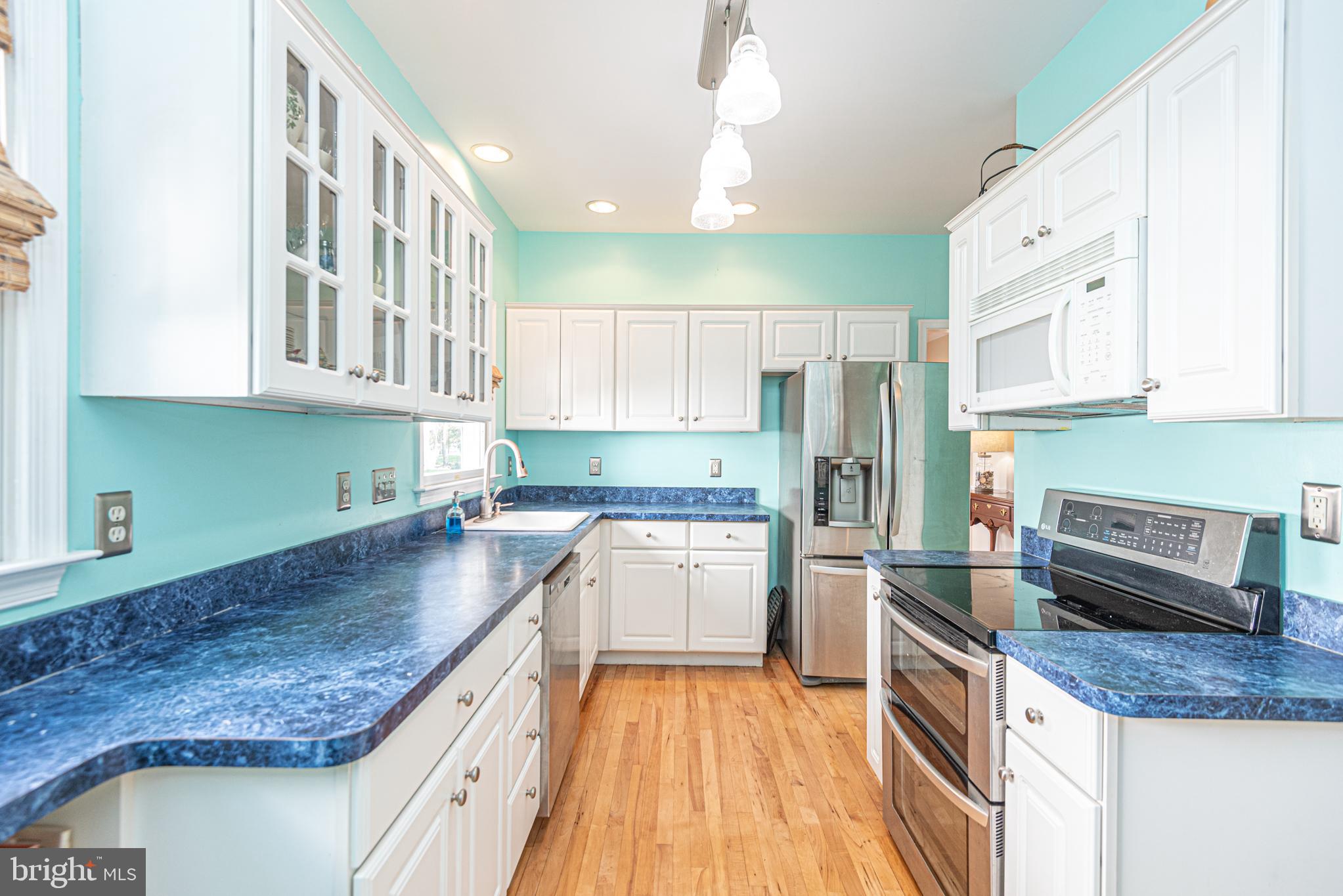 263 Oyster Shell Cove Bethany Beach, DE 19930 - Photo 12 of 50 a kitchen with stainless steel appliances granite countertop a refrigerator a sink dishwasher a stove and white cabinets with wooden floor