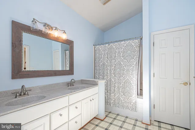 a bathroom with a granite countertop sink a mirror and a shower
