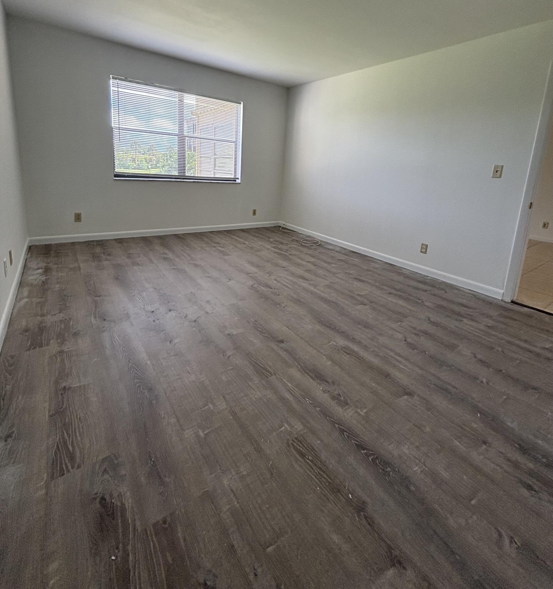 9355 Southwest 8th Street, Unit 216 Boca Raton, FL 33428 - Photo 11 of 19 an empty room with wooden floor and windows