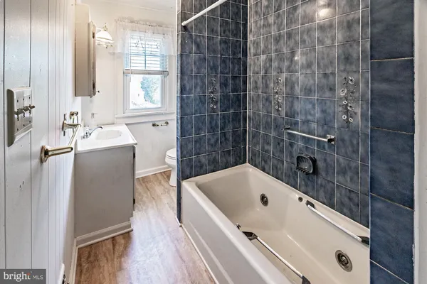 a bathroom with a tub a sink and wooden floor
