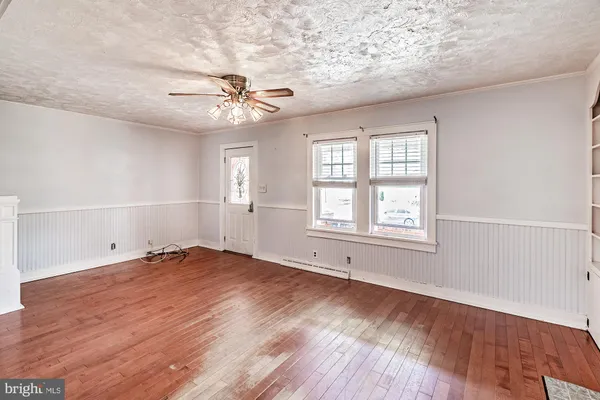 an empty room with wooden floor chandelier fan and windows