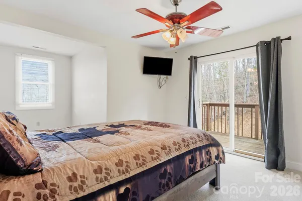 a bedroom with a large bed a flat tv screen and a window
