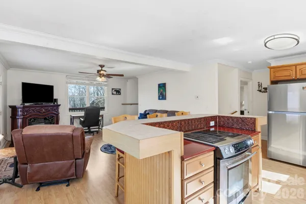a kitchen with stainless steel appliances granite countertop a stove refrigerator and a flat screen tv
