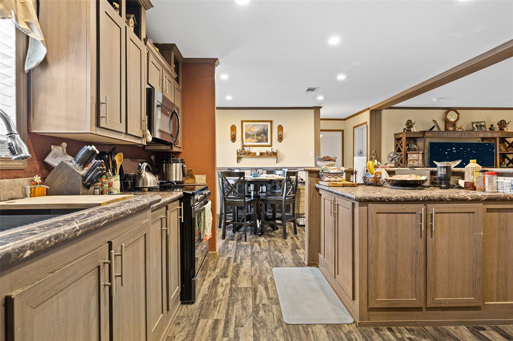 454 Geronimo Quitman, TX 75783 - Photo 18 of 37 a kitchen with stainless steel appliances granite countertop a refrigerator a sink dishwasher a stove and a dining table with wooden floor