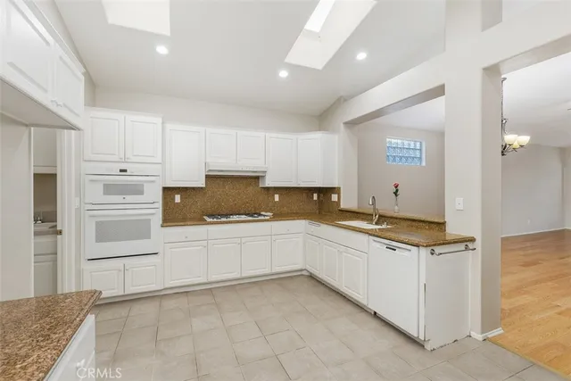 a kitchen with granite countertop a sink and white cabinets