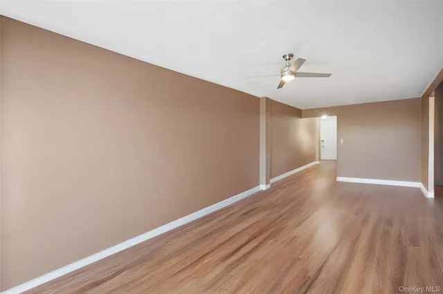 a view of empty room with wooden floor and ceiling fan