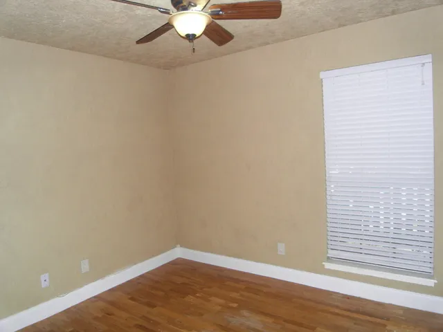 an empty room with wooden floor closet and windows