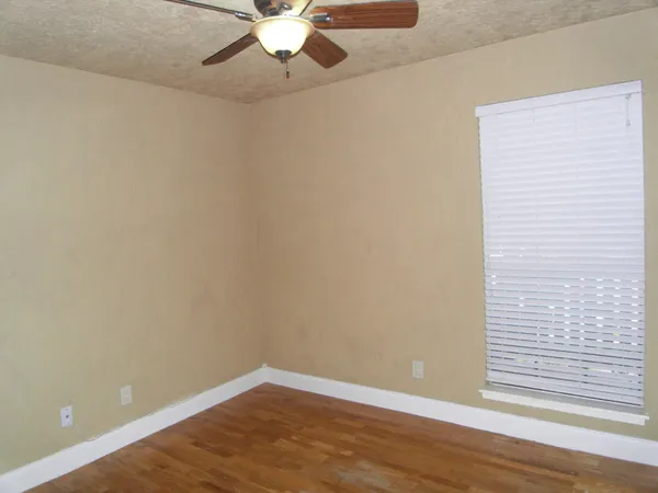 an empty room with wooden floor closet and windows